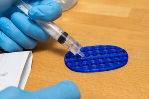 SoundBounce assembly; hand injects SoundBounce fluid into cellular housing.